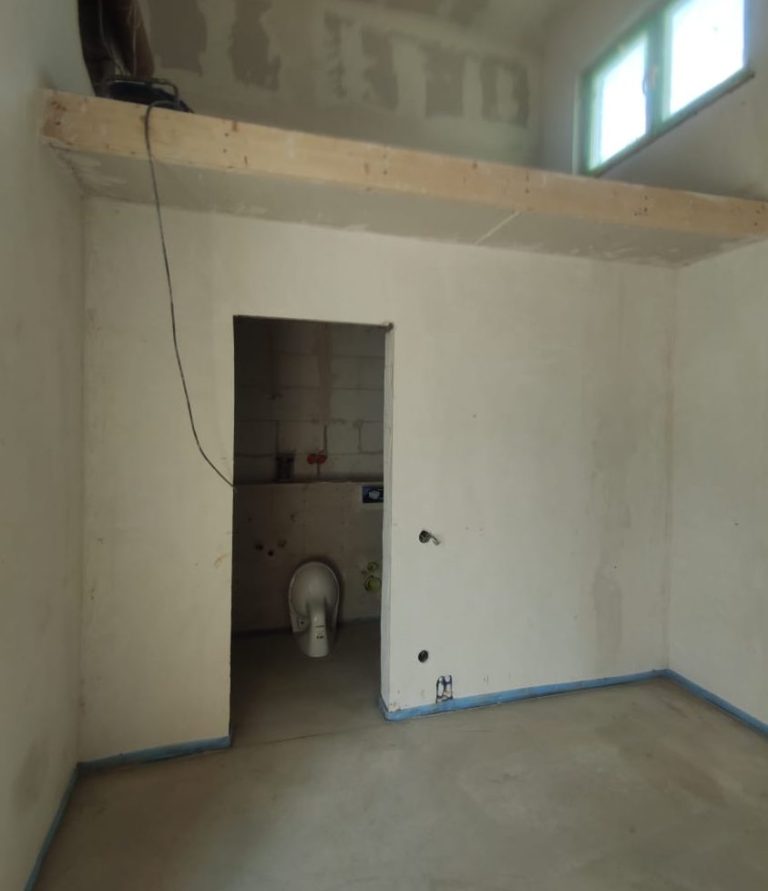 Leerer Raum mit einer Tür zum Badezimmer und einer Holzablage an der Wand.