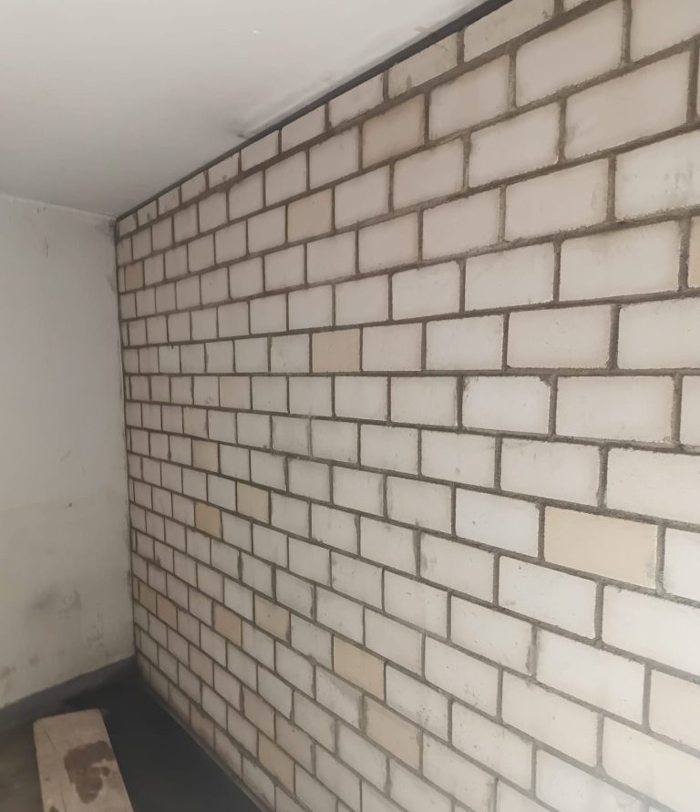 Wand mit Mauersteinen in neutralen Farben, teilweise schmutzig.